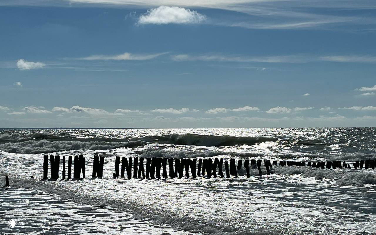 Штормовое море и старые деревянные палисады в воде: сильные волны, серебристые блики на поверхности и драматичное небо над Балтикой.