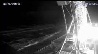 Вечерний кадр с веб-камеры санатория «Зеленоградск»: штормовое море у берега, освещённая конструкция и набережная.