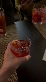 Короткое видео: несколько людей поднимают бокалы и рюмки за столом в тёплой компании внутри рюмочной «Критика Чистого».