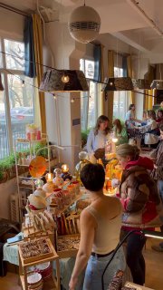 Внутренний вид мероприятия: торговые столы с хендмейдом и керамикой, продавцы и посетители под тёплым освещением в уютной обстановке.