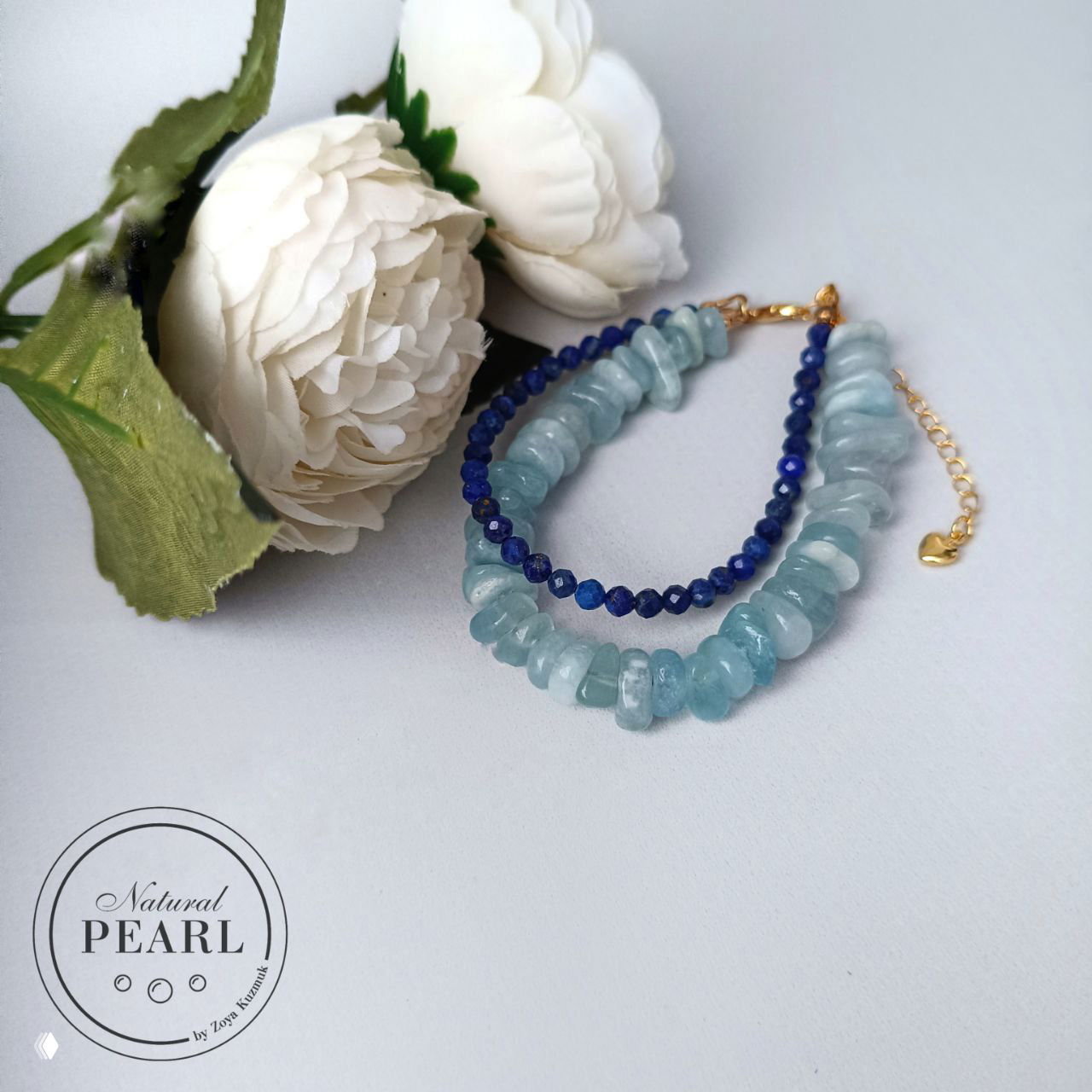Вид сбоку на тот же браслет: аквамариновые чипсы, огранённый лазурит и золотая цепочка-удлинитель в композиции с искусственными белыми цветами.