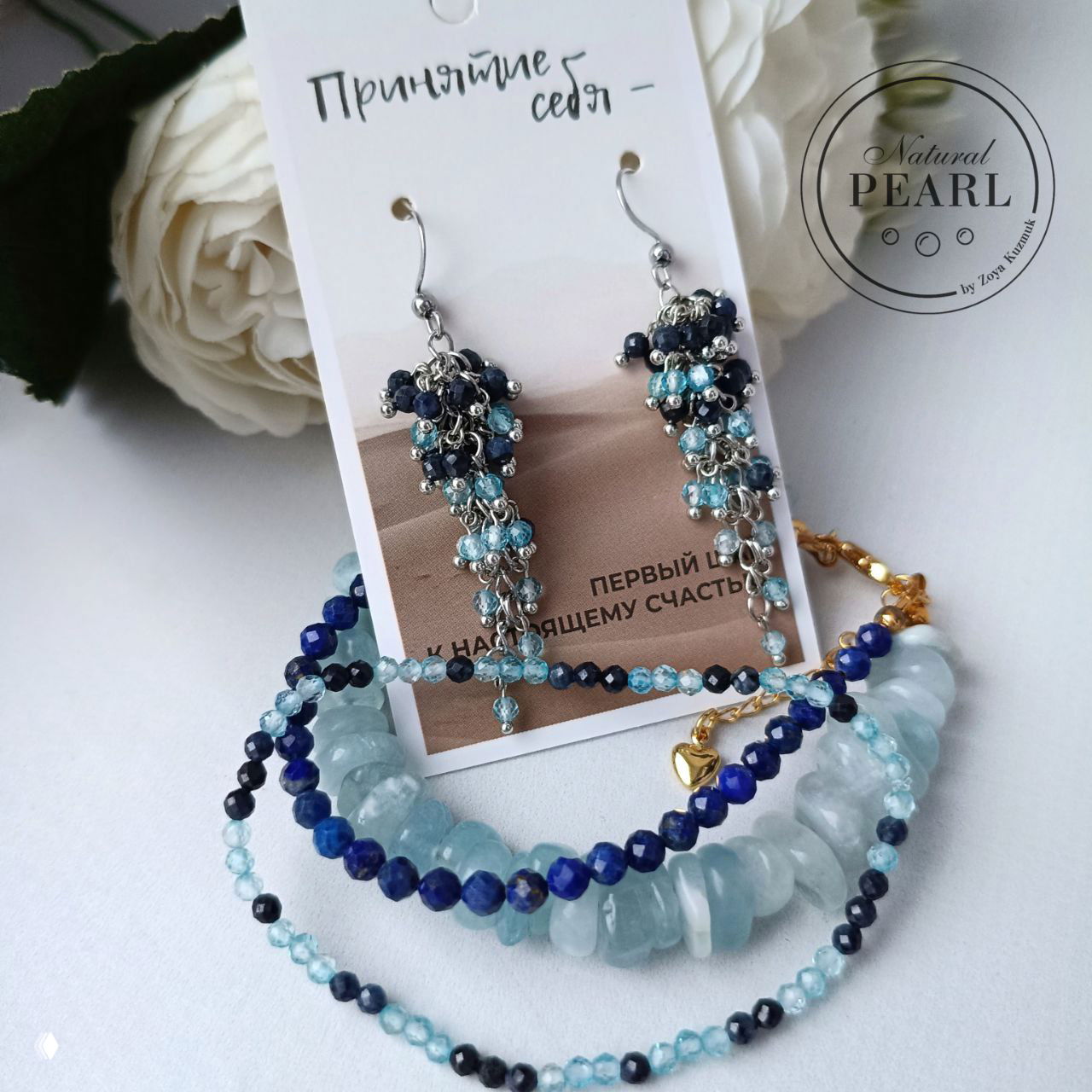 Серьги в кадре с комплектом браслетов из аквамарина, сапфира и топаза на белом фоне; видны фирменный логотип и композиция для каталога.