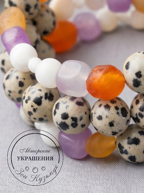 Крупный план бусин браслета «Радость»: видно пятнистую далматиновую яшму, полупрозрачный аметист, оранжевый агат и перламутр.