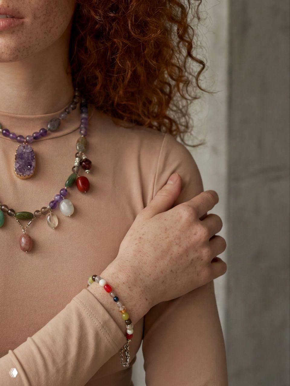 Крупный план шеи и груди модели с несколькими ожерельями из натуральных камней и крупным аметистовым кулоном, детализация фактур и сочетание форм.