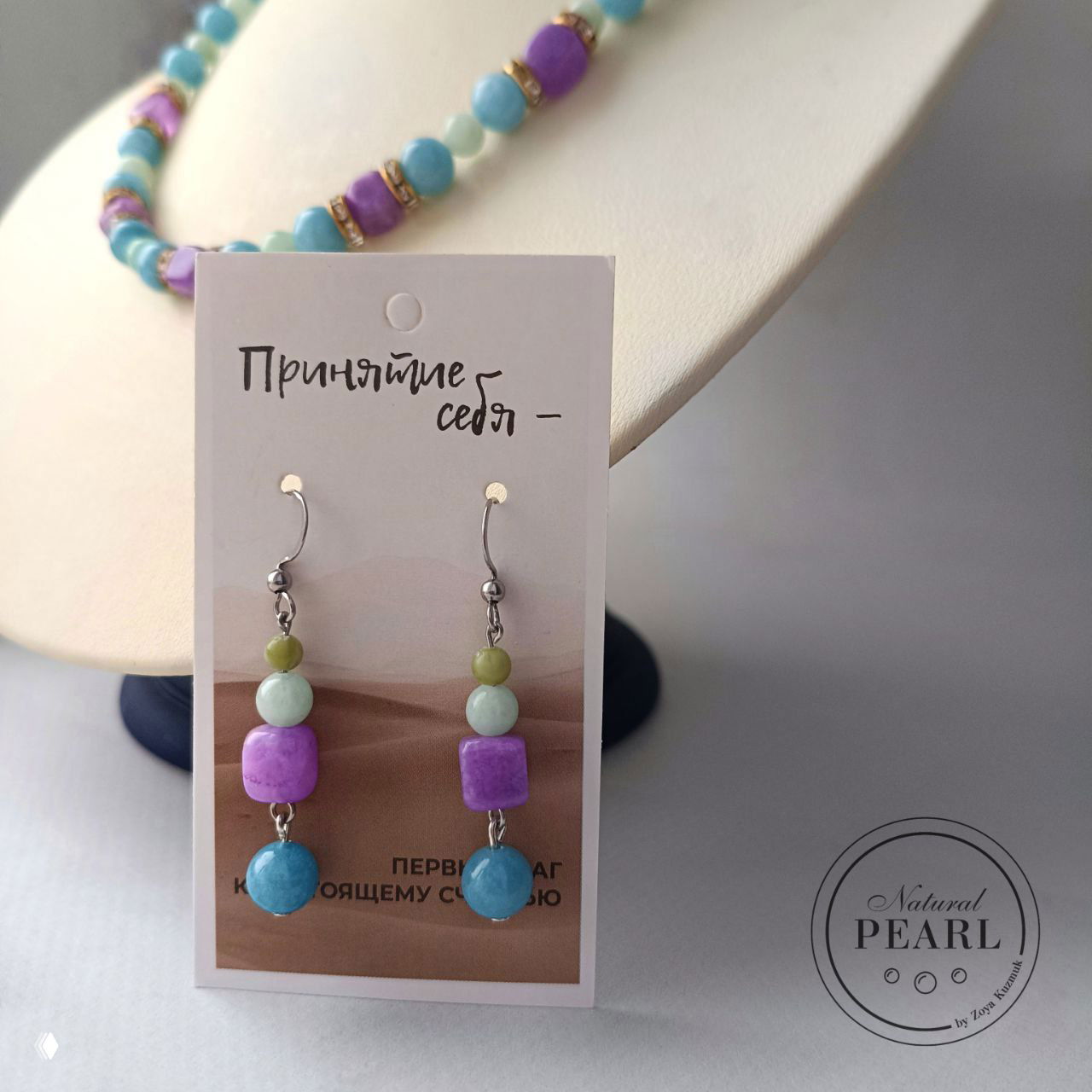 Серьги на демонстрационной карточке рядом с колье: бусины бирюзово‑фиолетовой гаммы, показаны форма и сочетание камней