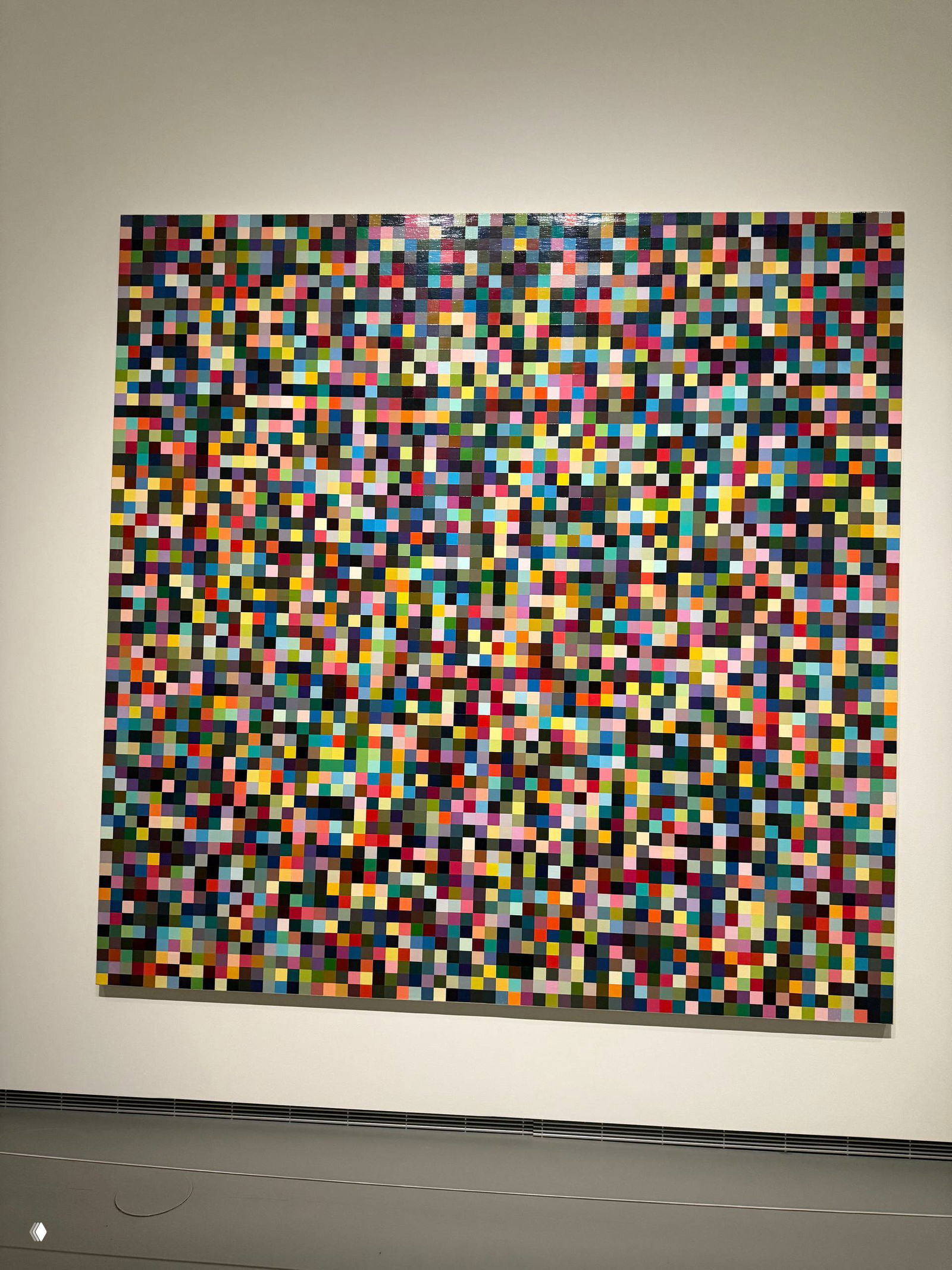Полотно, состоящее из множества цветных квадратов — геометрическая сетка и насыщенная палитра дают ощущение цифровой пикселяции и множественных чтений образа.