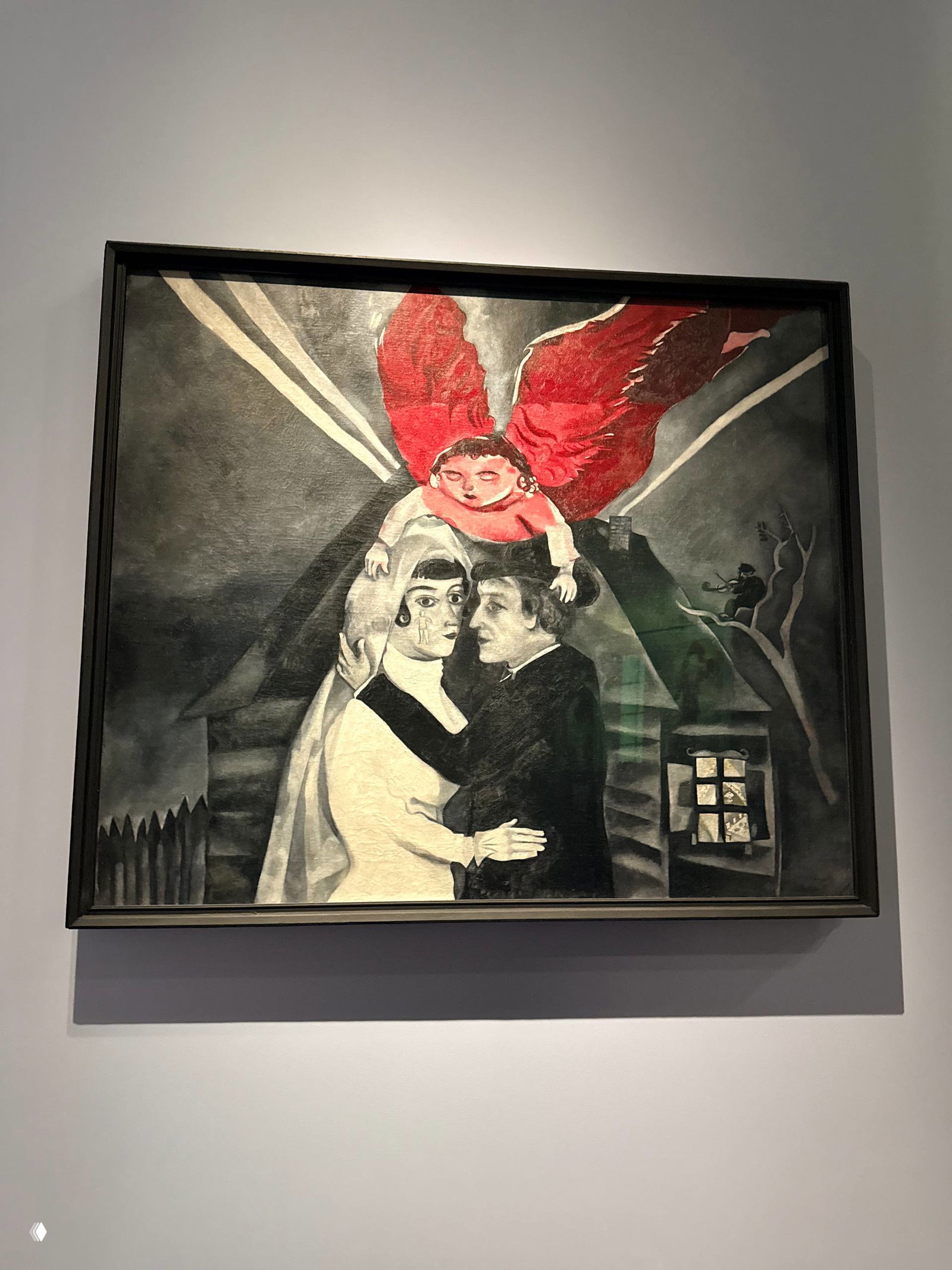 Монохромная композиция Шагала: пара обнимается под красными крыльями ангела, драматичный контраст и символизм страдания и защиты.