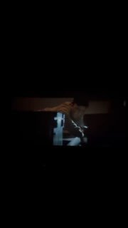 Тёмный кадр-стоп-кадр из фильма: силуэт человека в полутёмной сцене рядом с ярко освещённым вертикальным элементом, атмосферный фрейм рецензируемого фильма.