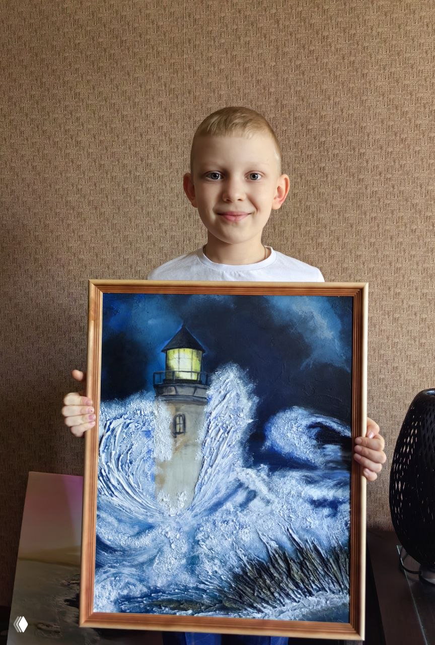 Мальчик держит в руках картину «Маяк» с мощными волнами и подсвеченным фонарём — авторская работа, вызывающая рассказы и воображение ребёнка.