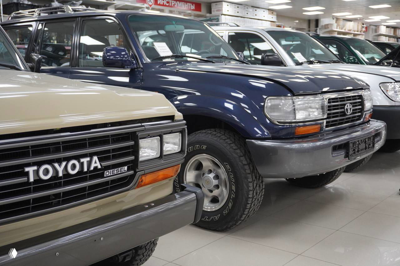 Фрагмент передних частей внедорожников: Toyota Land Cruiser и сопутствующие автомобили на выставке ретро и внедорожников в Горроще, акцент на решётке и колёсах.