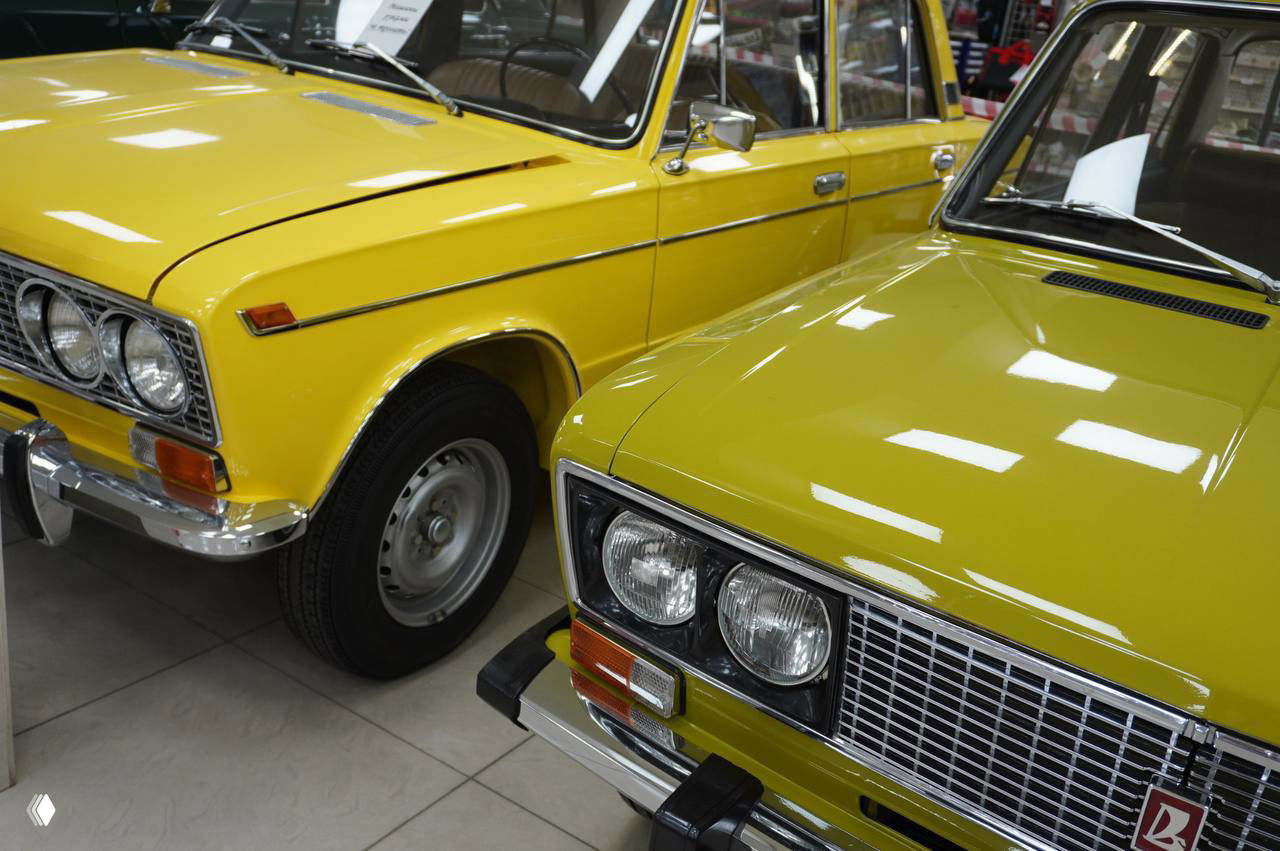 Крупный план жёлтых и зелёных кузовов советских автомобилей, отражения потолочного света на лаке и хромированные элементы бампера и решётки, экспозиция в Рязани.