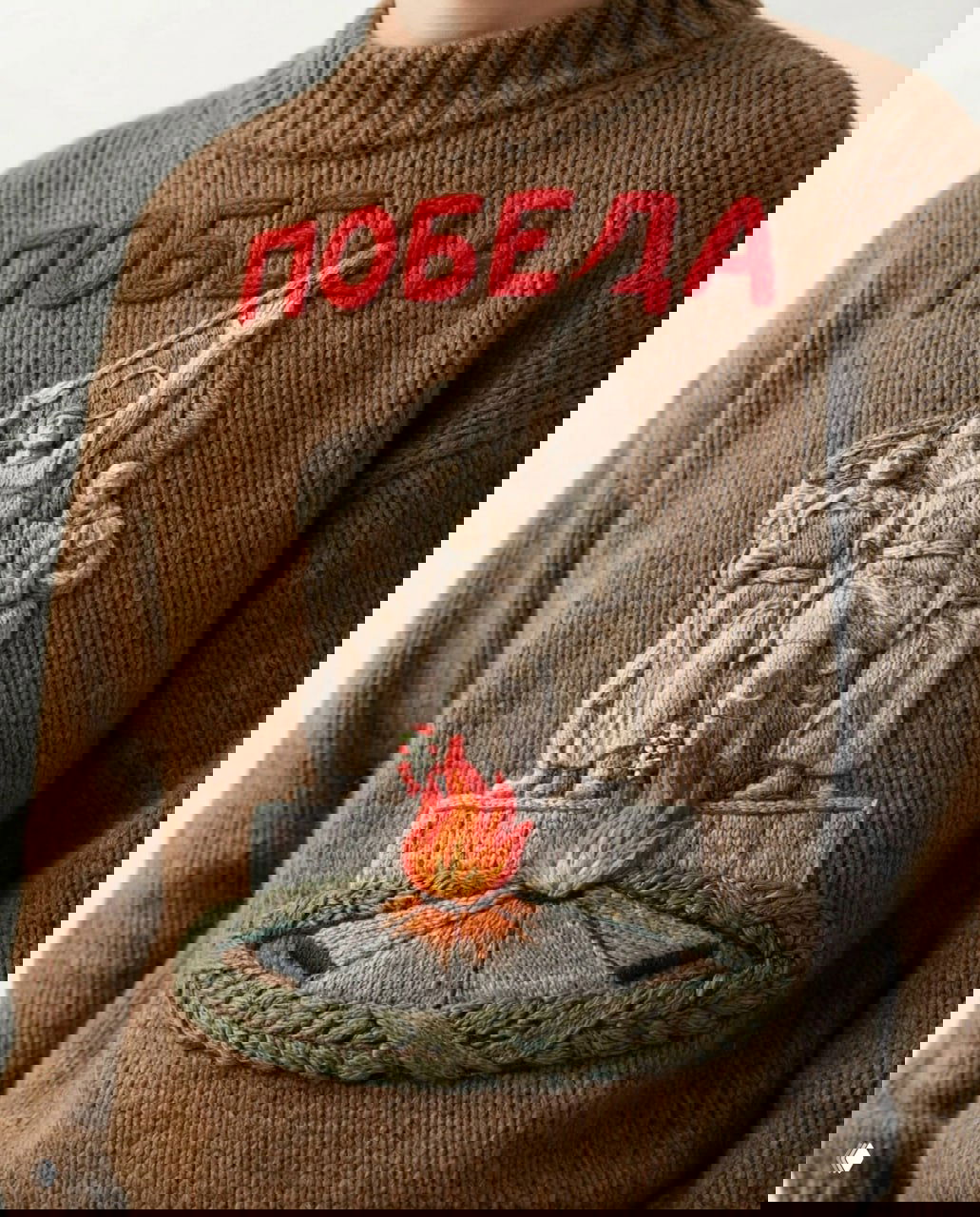 Коричневый свитер с крупной вышитой композицией и красной надписью «ПОБЕДА», изображающей монумент с фигурной группой и вечным огнём внизу.