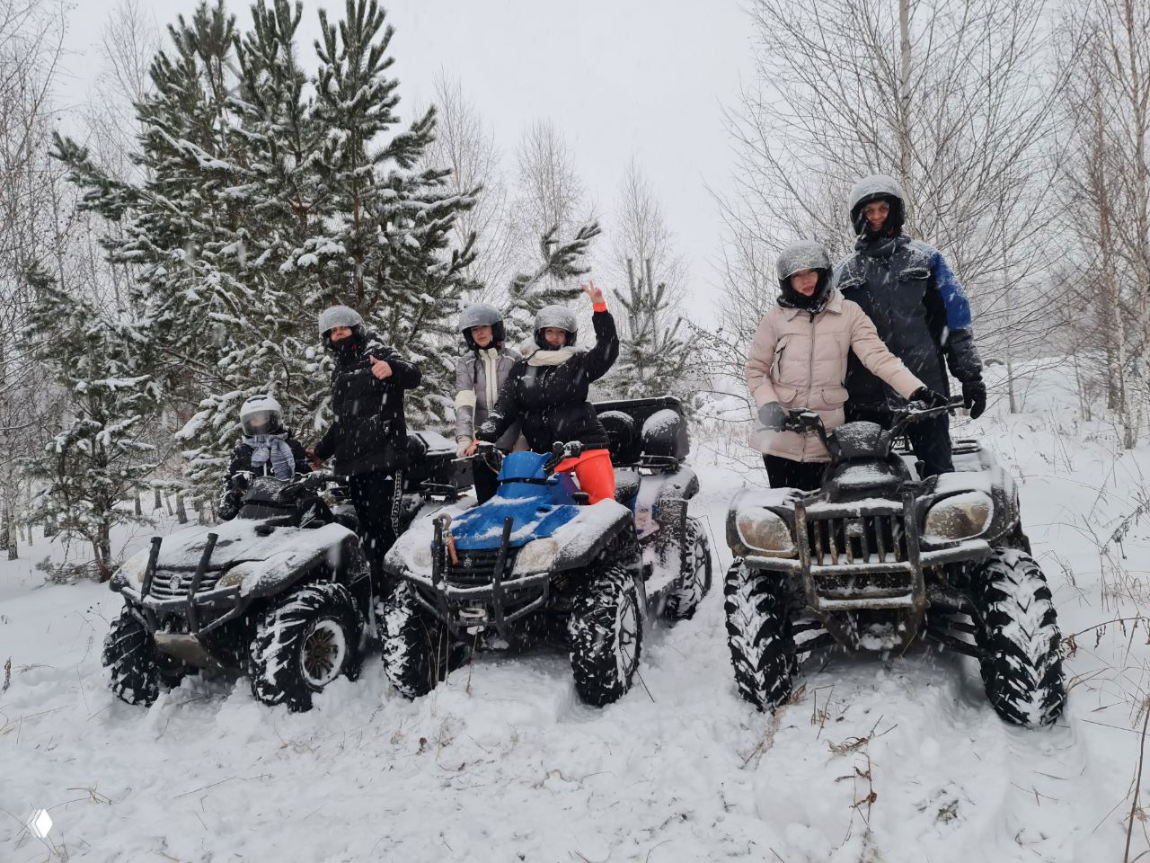Группа из нескольких квадроциклов и участников в снегу, люди машут руками стоя рядом с техникой; демонстрация групповых выездов и экипировки на прокате.