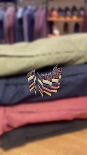 Фотография стопки лёгких слаксов разных летних оттенков в магазине DIGEL; видно разнообразие цветов и фактуры ткани.