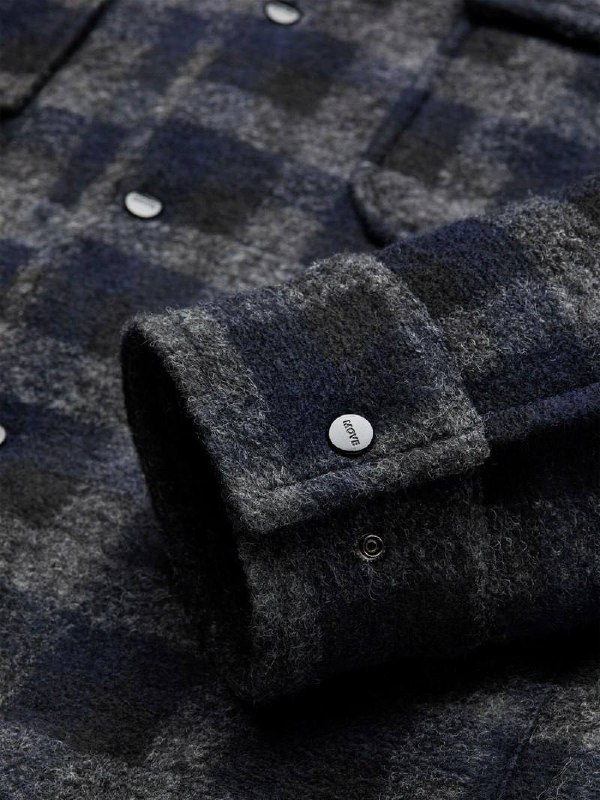 Детальное фото манжеты тёмного клетчатого овершота с металлической кнопкой MOVE: швы, текстура ткани и фурнитура крупным планом.