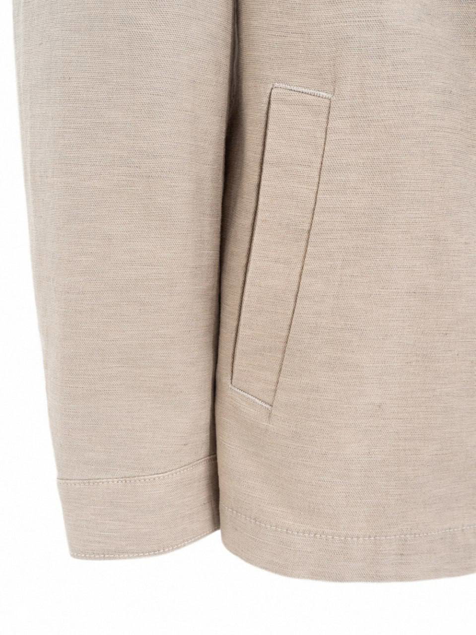 Крупный план светлой бежевой ткани и прорезного кармана: текстура материала и обработка краёв видны на белом фоне.