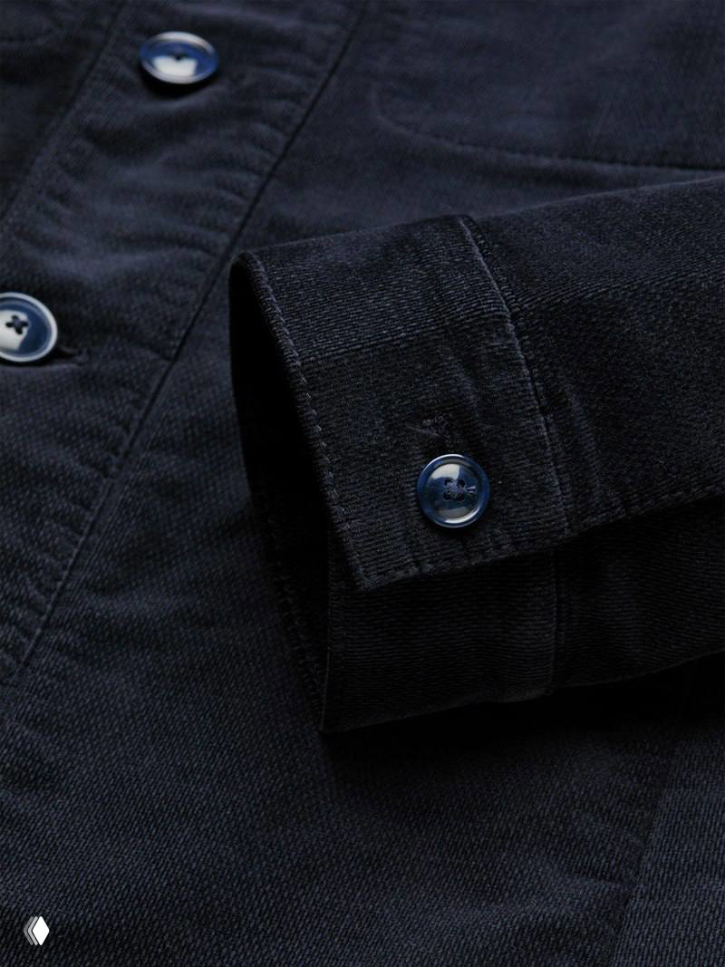 Крупный план тёмно-синей манжеты с синими пуговицами: фактура ткани, форма манжеты и фурнитура показаны детально для оценки изделия.