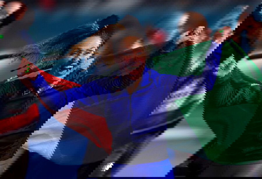 Франческа Лоллобриджида славно ликует с итальянским флагом после победы на дистанции 3000 м — крупный кадр радости спортсменки на льду.