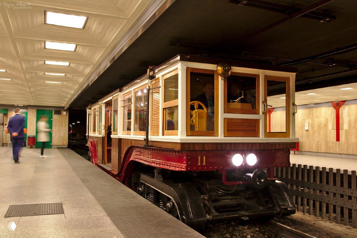 Восстановленный исторический вагон в метро с деревянной обшивкой, витражными окнами и ретро-освещением на платформе