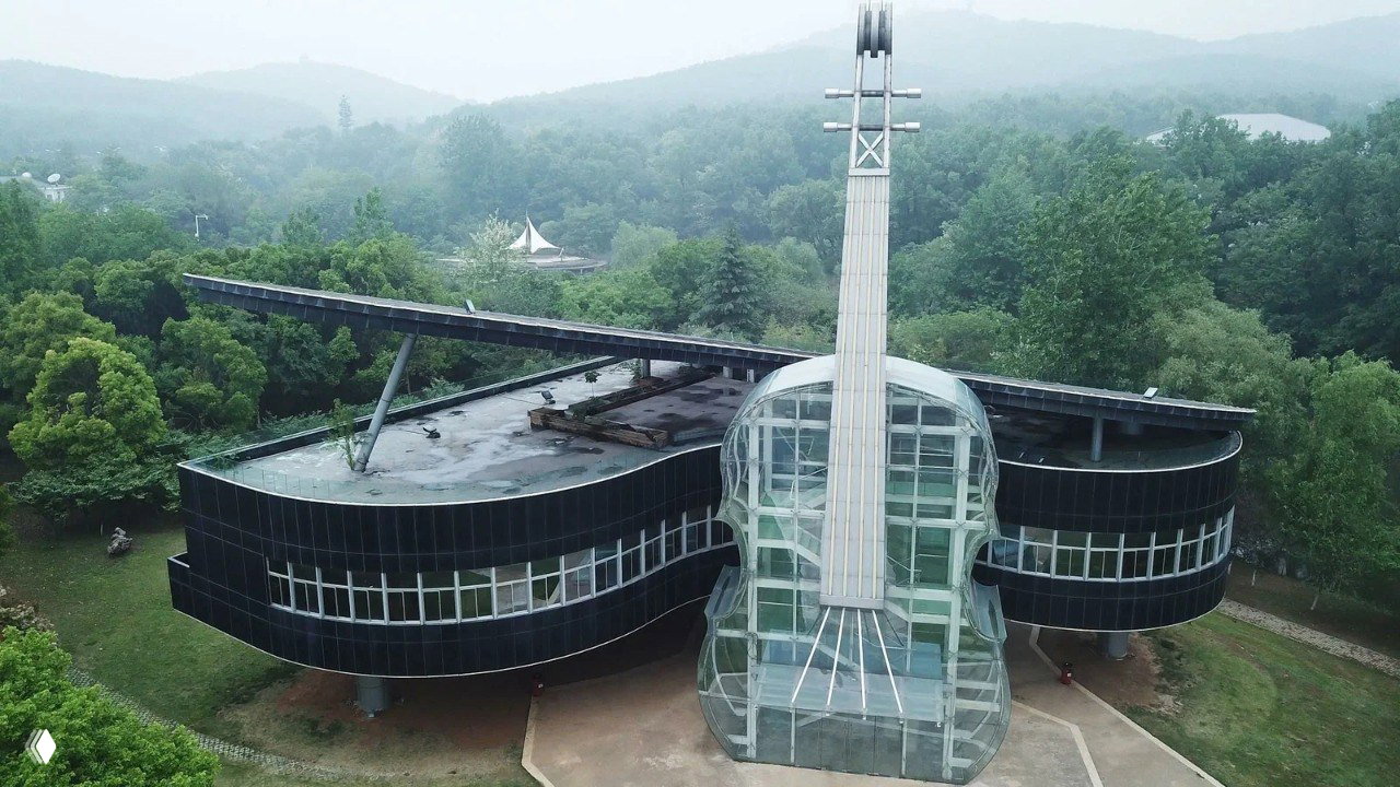 Дневной вид Piano house в провинции Аньхой: стеклянная скрипка у центрального фасада и вытянутое крыло в форме рояля среди зелёной местности