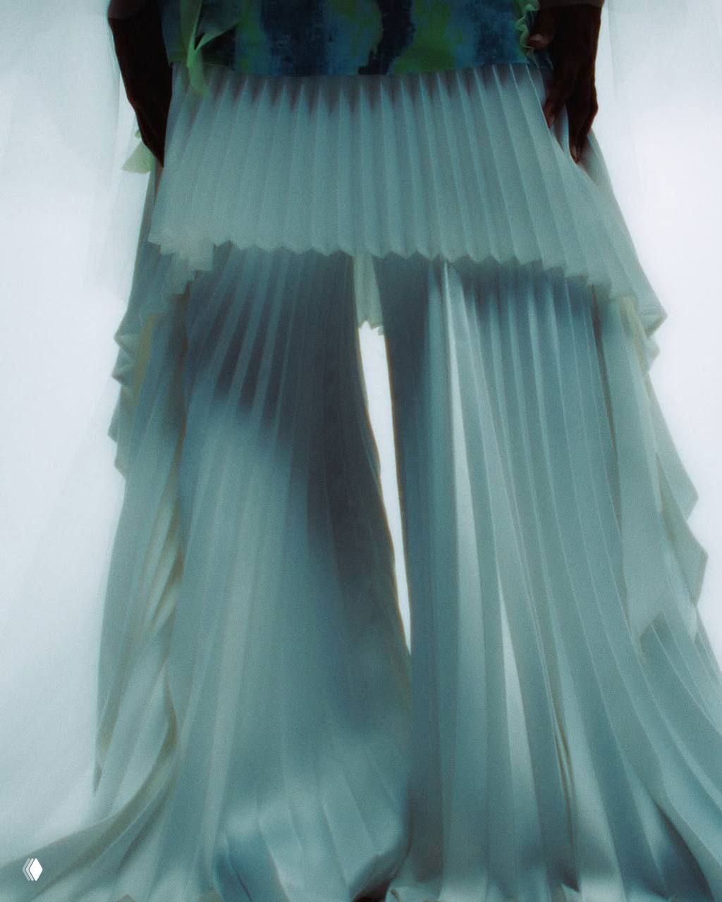 Крупный план складчатой плиссированной юбки/брюк из коллекции: белые мягкие складки, фактурная драпировка и игра света на ткани в студии.