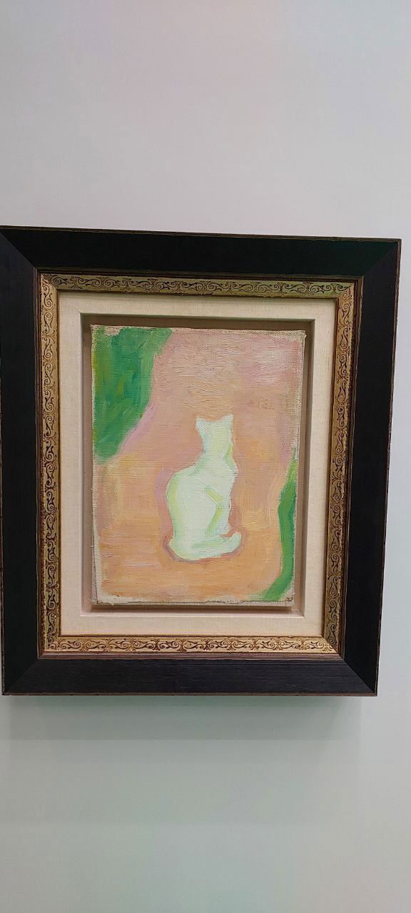 Фотография небольшой картины в тёмной резной раме: силуэт белой кошки на пастельном фоне, снятая в выставочном зале.