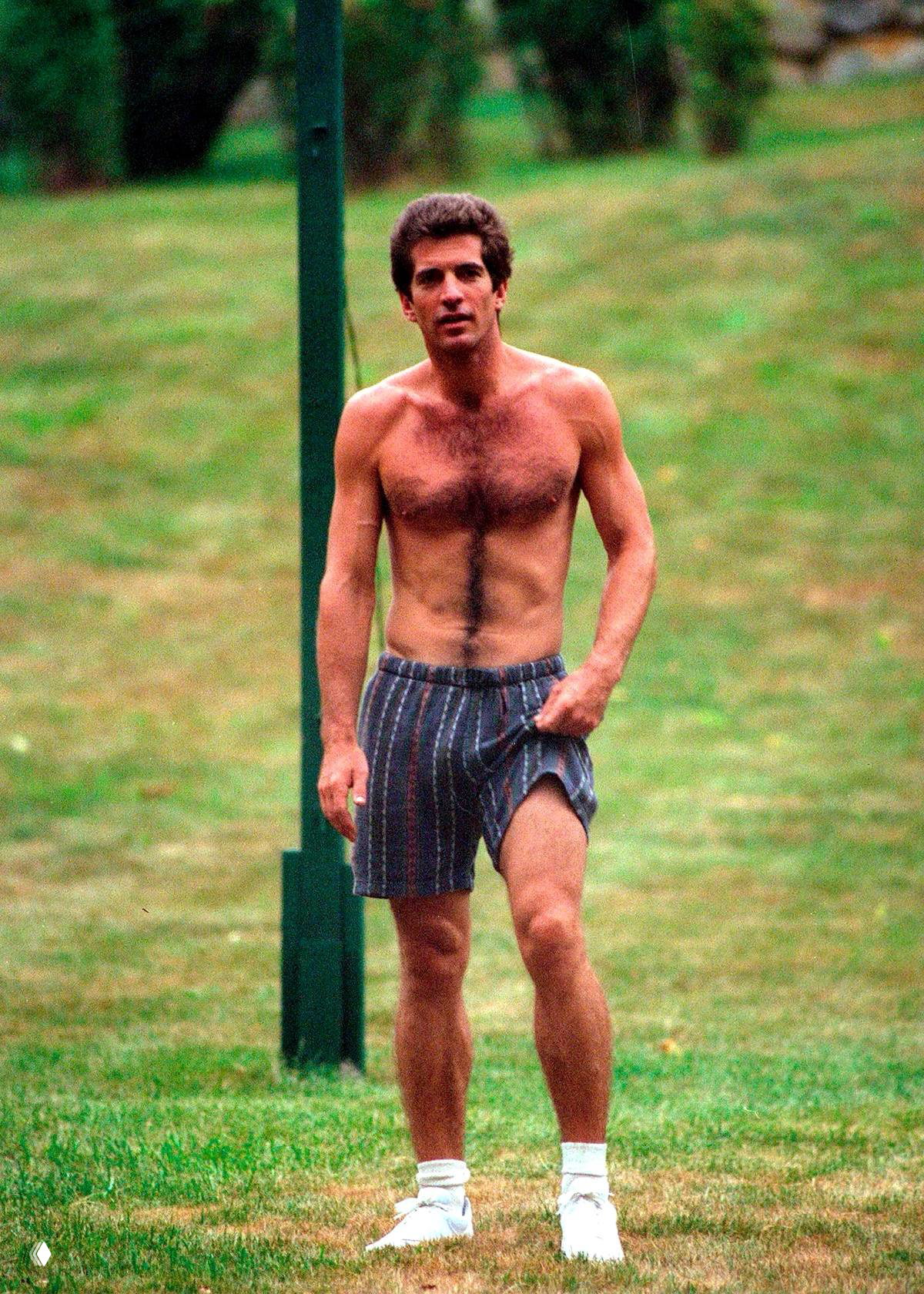 Мужчина без майки в свободных шортах идёт по травянистой территории — кадр подчёркивает спортивную и неформальную сторону гардероба.