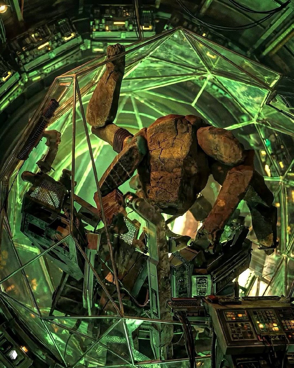 Рокки — каменистый инопланетянин в прозрачной защитной оболочке, крупный план показывает текстуру камня и механические элементы вокруг клетки.