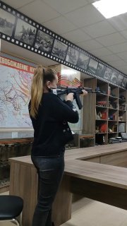 Женщина на внутреннем тире держит винтовку и целится; на заднем плане карта и стенды, кадр отражает момент турнира и личного инсайта о работе и жизни.