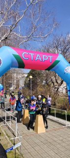 Стартовая арка «СТАРТ» и дети-участники соревнований по спортивному туризму на улице в Анапе; кадр с публикой и голыми деревьями в фоне.
