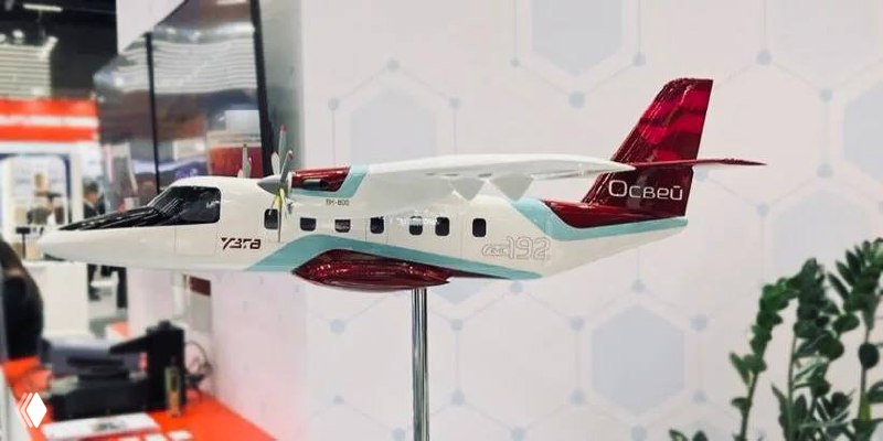 Макет самолёта «Освей» на выставочном стенде: бело-красно-бирюзовая модель малого пассажирского самолёта с надписью «Освей» на хвосте, вид сбоку.