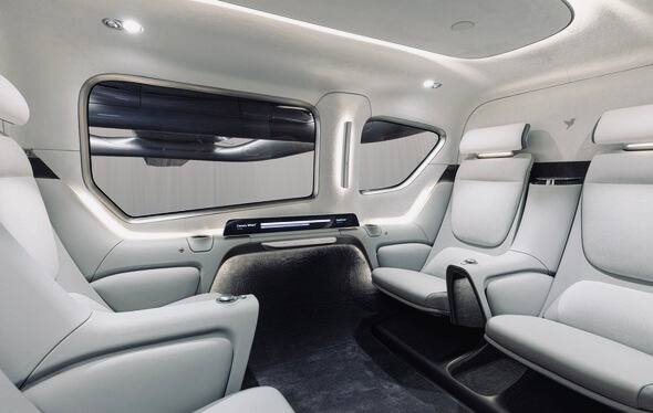 Интерьер пассажирского салона Valo с разделённой кабиной: шесть комфортных кресел в светлой отделке, вид на багажное пространство и отделение пилота.