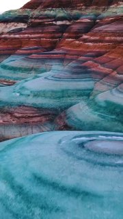 Фотография бентонитовых холмов в Юте: радужные слои глины и минералов, мягкие округлые формы и волнистый рельеф.