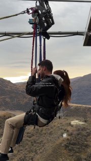 Два человека в страховочных поясах на качелях Nevis Swing, подвешенных над каньоном реки Невис у Куинстауна, горный пейзаж.