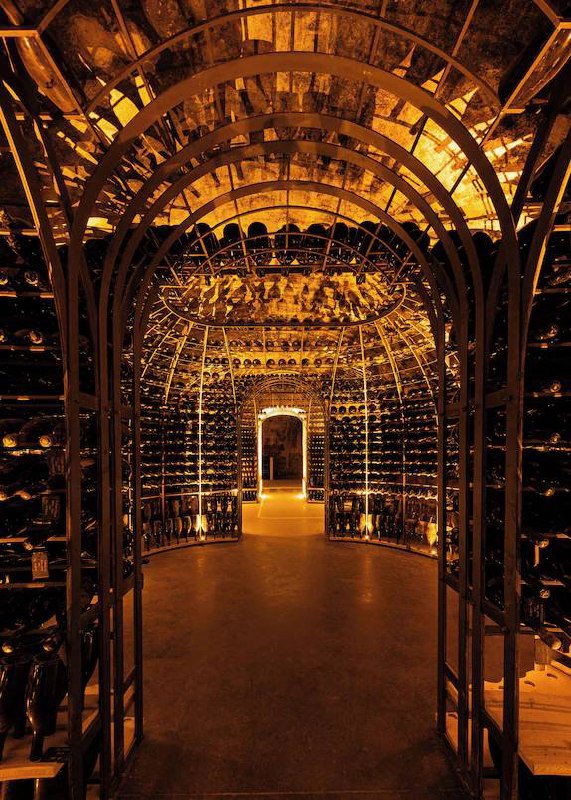 Винный погреб с высокими арками и сотнями бутылок при тёплой подсветке — показывает коллекцию и атмосферу дегустационной зоны Le 3.