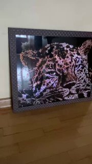 Фотография картины «Леопард» (40×50 см) в раме: стекло и стразы блестят на свету, работа стоит на полу в интерьере.