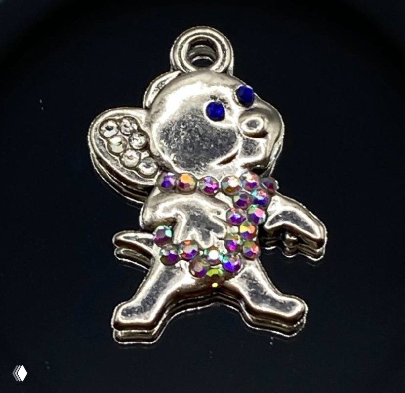 Крупный план того же металлического брелока‑мышки, украшенной разноцветными стразами на корпусе и глазках, на чёрном фоне для контраста.