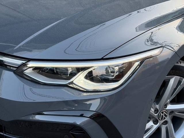 Крупный план передней фары Volkswagen Golf 2021 — светодиодная оптика, часть бампера и колеса видны; отражения неба на лаковой поверхности видны без царапин.