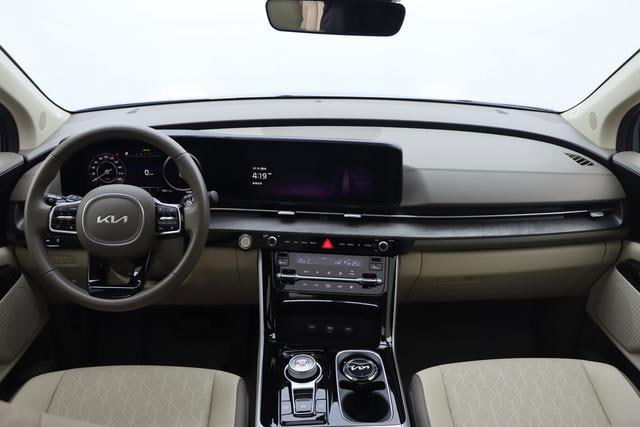 Салон Kia Carnival (март 2025) — панель приборов и центральная консоль, сенсорный дисплей и руль с логотипом KIA, видно состояние интерьера.