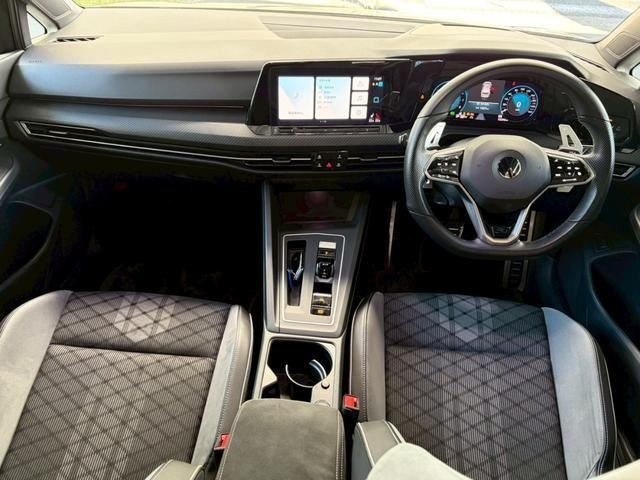 Салон Volkswagen Golf 2021: панель приборов и центральный тоннель, руль справа (правый руль), мультимедиа экран, передние кресла в тканевой отделке, состояние салона видно.