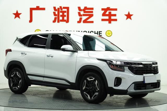 Kia Seltos в салоне демонстрационного зала, ракурс со стороны передней части; хорошо видны решётка, фары и контур капота и крыши.