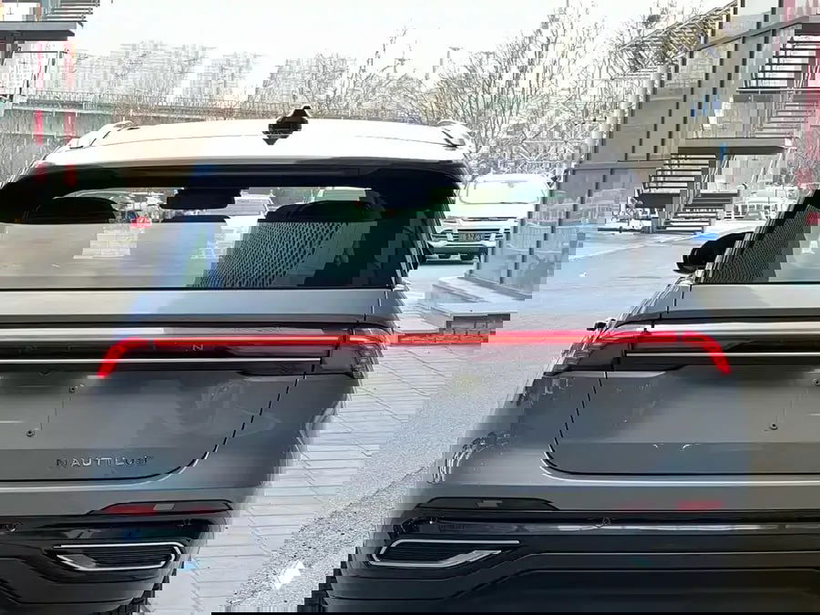 Вид сзади на Lincoln Nautilus II: широкая светодиодная планка фонарей, багажник и задняя часть кузова в сером цвете на парковке