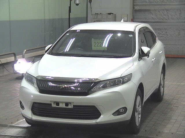 Угол спереди белого Toyota Harrier 2017, видна решётка радиатора и фары; фото сделано в закрытом ангаре без регистрационных знаков.