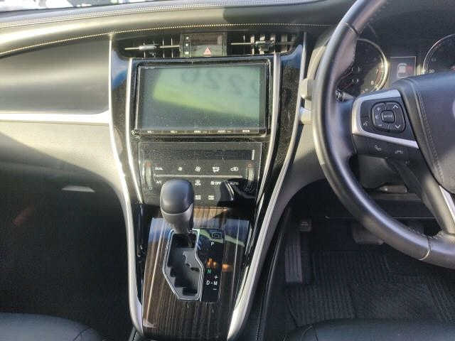 Салон Toyota Harrier 2017: центральная консоль, рычаг КПП, мультимедиа-панель и рулевое управление на фото в светлом салоне.