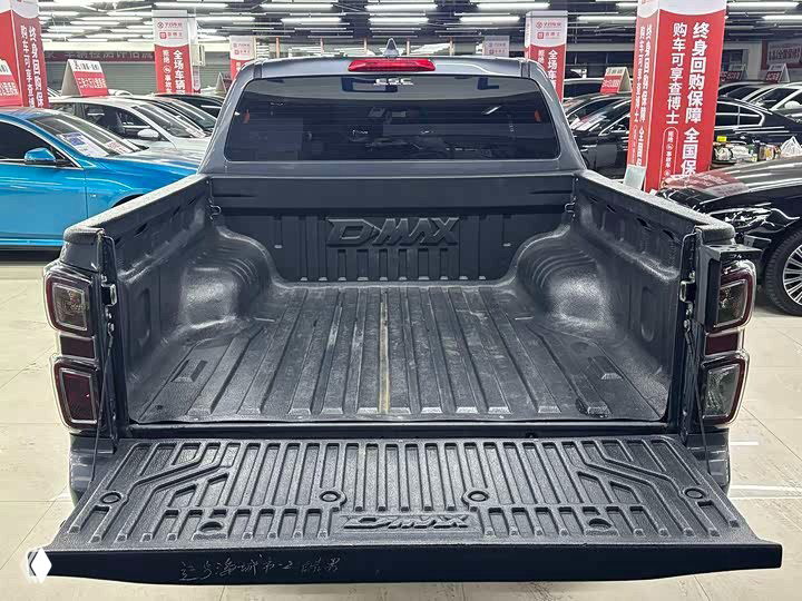 Открытый борт пикапа Isuzu D‑MAX, вид на грузовую платформу с пластиковым вкладышем; фото из автосалона показывает состояние кузова и борта.