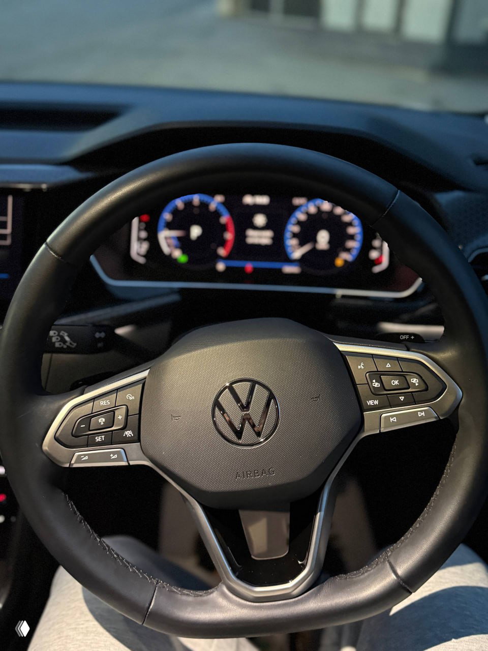 Боковой вид автомобиля Volkswagen T‑Cross 2023 года на фоне городских построек; акцент на профиле дверей и дорожном просвете кроссовера.