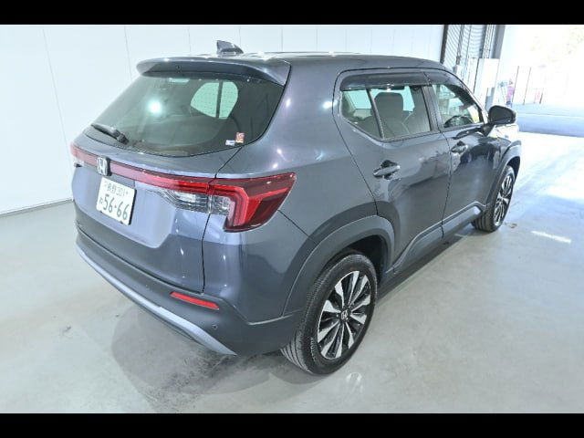 Honda WR‑V 2024, вид сзади‑слева в шоуруме; хорошо виден профиль кузова, багажник и задние фонари на светлом фоне.