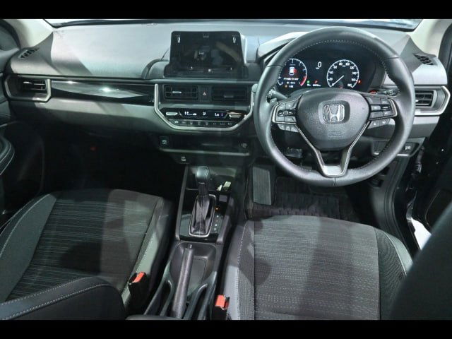 Салон Honda WR‑V 2024: передняя панель, руль с эмблемой Honda, дисплей мультимедиа и тканевые сиденья в хорошем состоянии.