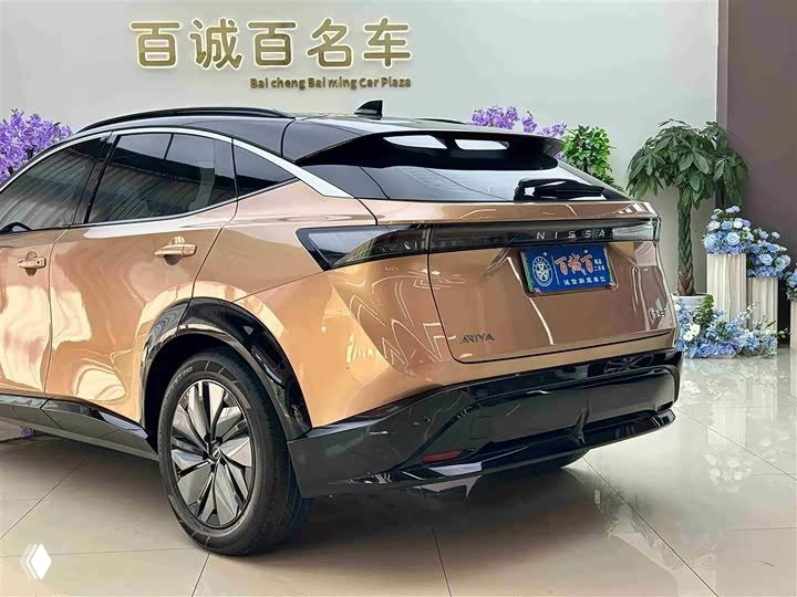 Крупный план кормовой части Nissan Ariya: задний бампер, низкий спойлер и глянцевая отделка в условиях автосалона.