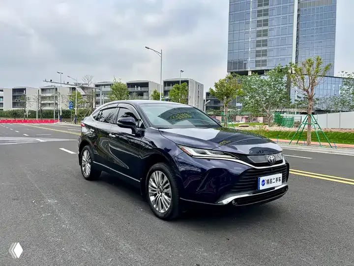 Ещё один общий ракурс тёмно-синего Toyota Harrier 2022 на городской улице, автомобиль стоит под углом, видна передняя часть и боковая линия.